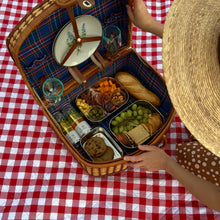 Load image into Gallery viewer, Premade charcuterie picnic, meat, cheese, crackers, fruit, cookies, in picnic basket. being opened by girl in straw hat.