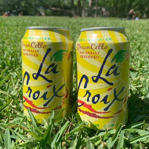 Two cans of lemoncello La Croix sparkling water in green grass.